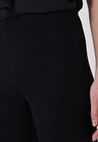 Zwarte broek met een visgraatpatroon, uitgevoerd in een textuurstof. Het ontwerp heeft een getailleerde taille en een gladde silhouet.