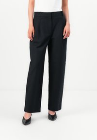 Black tailored trousers with a high waist, pleats, and straight legs. Made from a smooth fabric, featuring a classic design and minimal hardware.