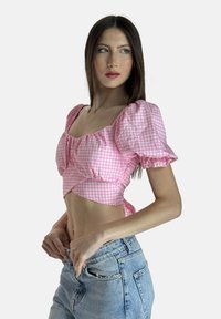 Rosa Gingham-Crop-Top mit Puffärmeln und Raffung. Kombiniert mit hellblauen High-Waist-Jeans im Five-Pocket-Stil.