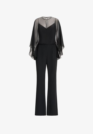 Combinaison noire avec une superposition de cape transparente et fluide, décolleté en V et pantalons à jambes larges, fabriquée dans un tissu lisse au design minimaliste.