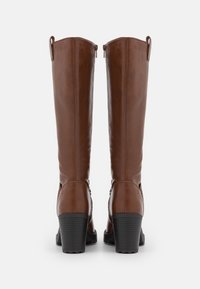 Bruine leren laarzen tot de knie met een gladde afwerking, ronde neus, blokhak en decoratieve zijaccenten; inclusief achterste lussen om aan te trekken.