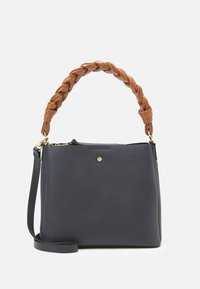 Marinblå tote-väska med en strukturerad form, försedd med ett flätat handtag i brunt läder och en gyllene hexagonaccent på framsidan.