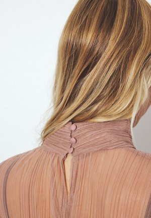 Blush-colored dress with vertical pleats, high collar, and back button closure. Sheer texture enhances design details and curvature.