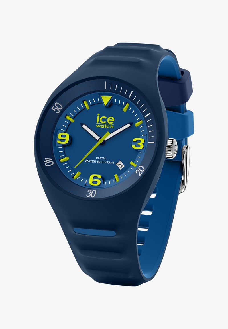 Zils silikona rokas pulkstenis ar apaļu seju, dzelteniem akcentiem un ūdensizturību līdz 10 ATM. Tam ir drosmīgi stundu rādītāji un datuma displejs.