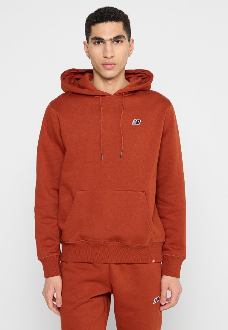 Sweatshirt en orange rouille, mélange de coton, avec une poche avant, une capuche à cordon de serrage, des poignets côtelés et un petit logo noir sur la poitrine.