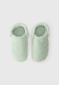 Gröna tofflor med fleecefoder, mjuk textur, rundad design och öppen bakdel för enkel påtagning. Utsidan har ett fluffigt utseende.