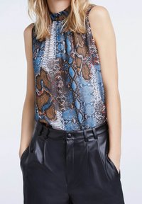 Top senza maniche caratterizzato da un motivo in pelle di serpente blu, marrone e bianco; materiale morbido; scollatura alta; abbinato a pantaloni in pelle nera.