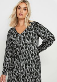 Sukienka z długim rękawem w szarym kolorze, z czarno-białym nadrukiem zwierzęcym, dekoltem w kształcie litery V, zapinana na guziki z gromadzonym detalem na ramionach. Gładka faktura materiału.