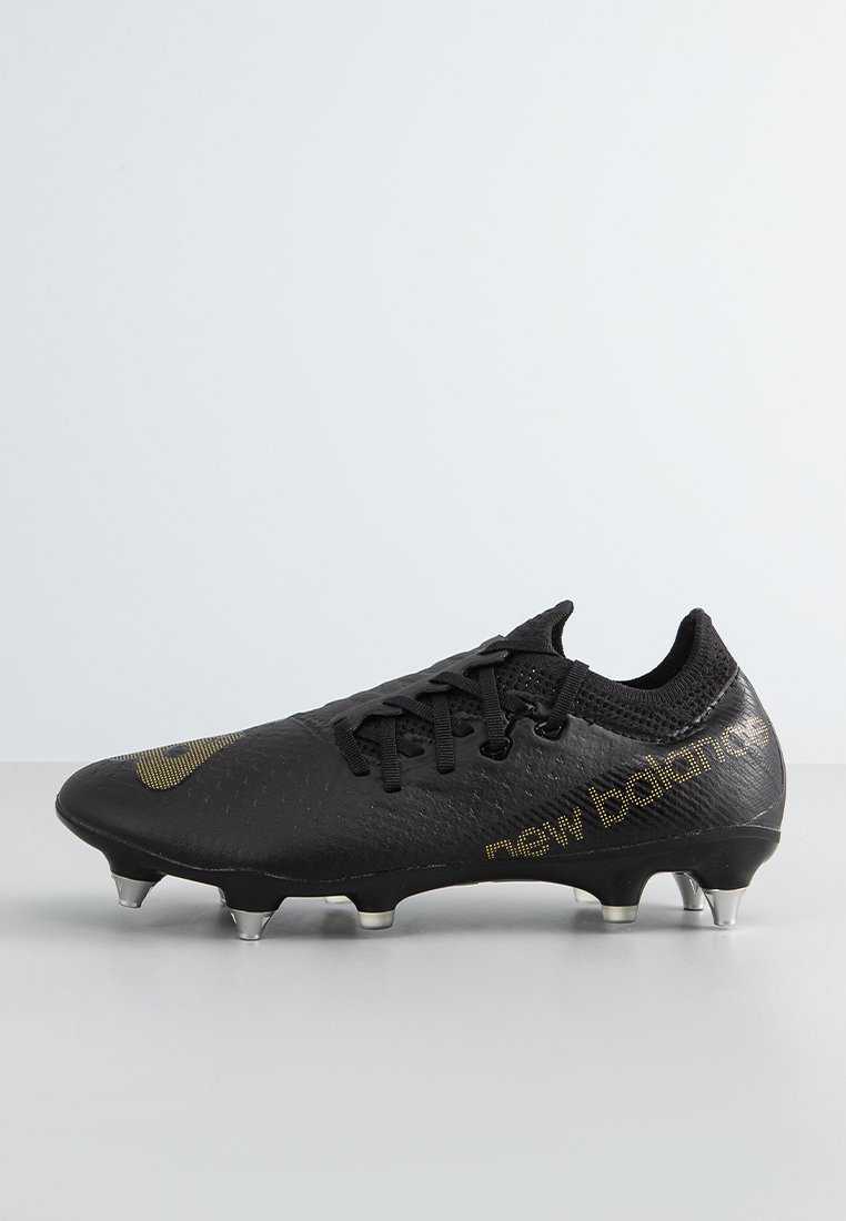 Botte de football noire en matériau synthétique texturé. Dotée d'un laçage et d'accents dorés sur le logo et le design. Semelle avec crampons métalliques.