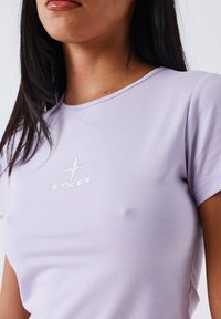 Camiseta lila hecha de una tela suave, con cuello redondo y mangas cortas, con el logotipo bordado en blanco "PXP" en la parte frontal.