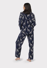 Marine blauwe pyjama set met een giraffe patroon; lange mouwen en broek, zachte stof met een relaxte pasvorm en zonder zichtbare sluitingen.