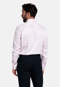 Lichtroze longsleeve shirt met een klassieke kraag, met knoopsluiting aan de manchetten en een gladde textuur, gecombineerd met donkere broek, gezien vanuit de rug.