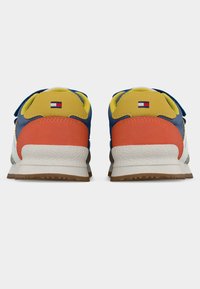 Πολύχρωμα αθλητικά παπούτσια με υλικά σε μπλε, κίτρινο, πορτοκαλί και λευκό. Κείμενα χαρακτηριστικά με λαστιχένια σόλα και λεπτομέρεια λογότυπου στη φτέρνα.