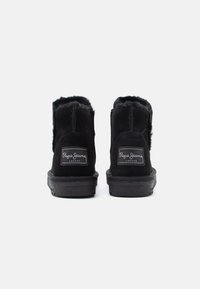 Czarne zamszowe botki za kostkę z miękkim futerkiem w środku, z okrągłym noskiem i gumową podeszwą. Z akcentem w postaci metki z logo z tyłu.