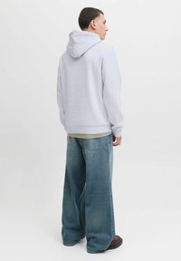 Lys grå hætte sweatshirt med en afslappet pasform, ribstrikkede manchetter og talje. Kombinationen er afsluttet med brede blå denimjeans.