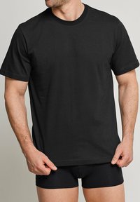 Black cotton t-shirt with short sleeves and a round neck, featuring a classic cut and smooth texture, displayed with matching black shorts.