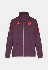 Giacca sportiva bordeaux con colletto alto, chiusura con zip, strisce rosse adidas e logo del Bayern Monaco. Tessuto liscio con polsini elasticizzati.