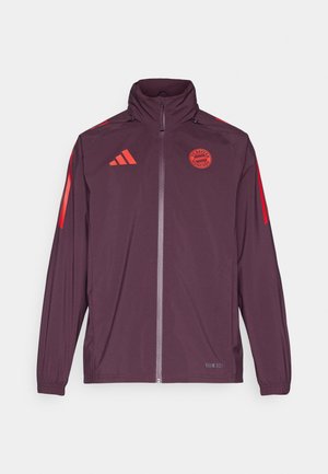 Giacca sportiva bordeaux con colletto alto, chiusura con zip, strisce rosse adidas e logo del Bayern Monaco. Tessuto liscio con polsini elasticizzati.