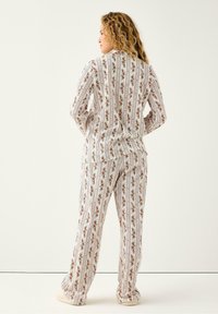 Pyjamasæt med blomstermønster i let stof. Langærmet skjorte med krave og matchende bukser, begge med lodrette striber og små blomster.