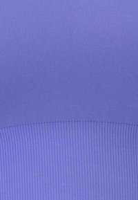 Gros plan sur un tissu côtelé bleu montrant des motifs de tricot horizontaux et verticaux avec un léger détail de couture près du centre.