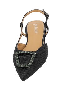 Zapato negro de slingback tejido con punta afilada, decorado con una hebilla rectangular de piedra preciosa verde, sobre una plantilla color beige.