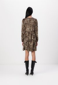 Φόρεμα με λεοπάρ σχέδιο, μακριά μανίκια, μαζεμένη μέση και φάσα φούστα. Συνδυασμένο με μαύρες μπότες με τακούνι μέχρι το γόνατο.