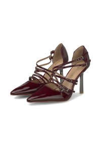 Scarpe con tacco alto in pelle verniciata borgogna con punte appuntite, multiple cinghie sottili alla caviglia e una finitura lucida. Presentano accenti metallici.