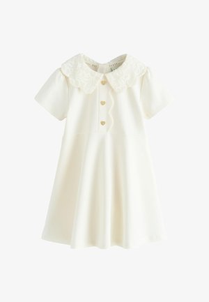 Crèmekleurige babyjurk met korte mouwen, een geschulpte bloemenkraag, gouden hartvormige knopen aan de voorkant en een uitlopende rok.
