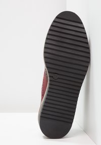 Sneakers bordeaux avec un cuir texturé en haut, présentant des détails perforés. Semelle en caoutchouc contrastée avec un motif de semelle. Taille 37 indiquée.