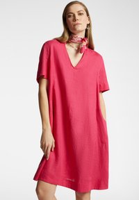 Abito in lino rosa con maniche corte e scollatura a V profonda, dotato di tasche laterali e una silhouette A-line rilassata. Tessuto morbido con decorazioni minime.