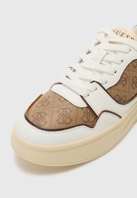 Braune und weiße Sneaker mit einem Obermaterial aus glattem Leder, gemusterten Stoffseitenteilen, runder Zehenpartie und strukturiertem Sole. Schnürsenkel und Logo sind sichtbar.