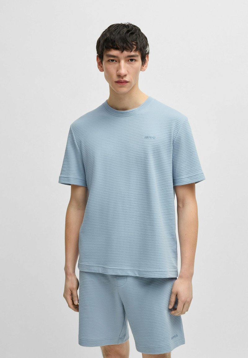 T-shirt azzurro chiaro a maniche corte con texture abbinato a pantaloni corti, dotato di scollatura rotonda e branding discreto sul petto.