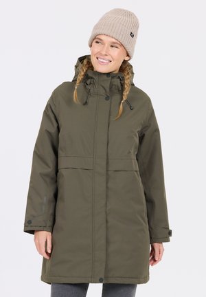 Lange olijfgroene parka met een trekkoordcapuchon, drukknoopsluiting en elastische manchetten. Draagt een lichtbeige gebreide beanie.