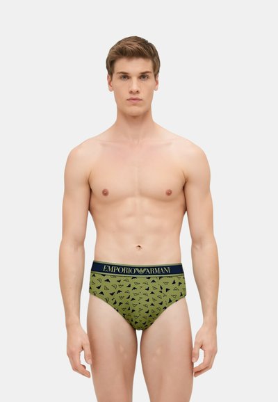 Slip in cotone verde con un motivo di piccoli loghi neri. Presenta un elastico blu navy con il marchio "Emporio Armani".