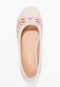 Béžová plochá obuv s kulatou špičkou, vyrobená z surového materiálu, s výřezovým květinovým designem na bocích a malou dekorační mašlí vpředu.