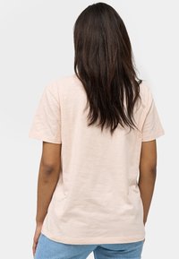 Lichtroze t-shirt met korte mouwen en een losse pasvorm, gemaakt van zachte stof. De achterkant heeft een eenvoudig ontwerp en een klassieke ronde hals.