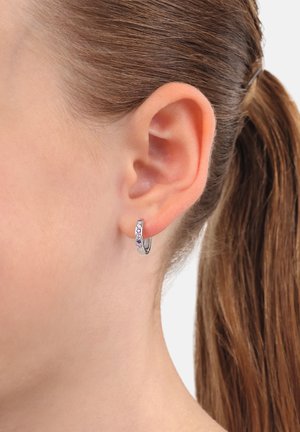 Orecchino a cerchio in argento con pietre multicolori incastonate, che presenta una superficie liscia e lucida e un design circolare compatto.