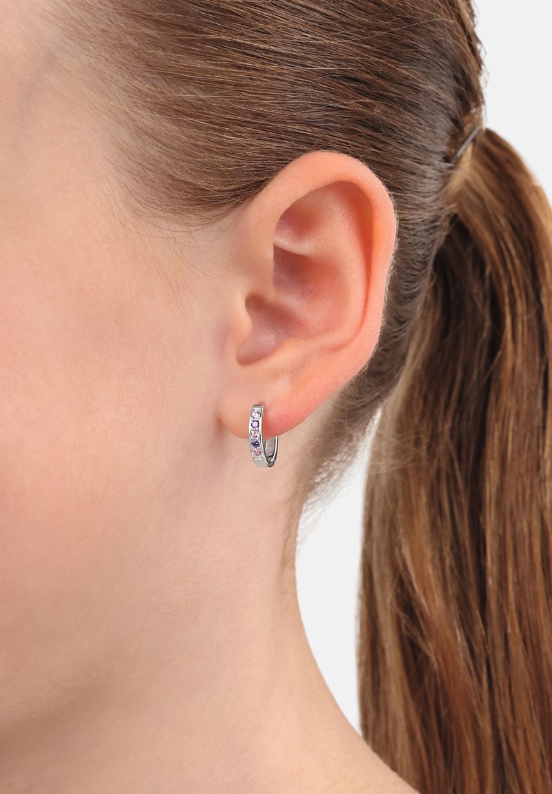 Orecchino a cerchio in argento con pietre multicolori incastonate, che presenta una superficie liscia e lucida e un design circolare compatto.