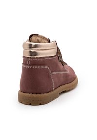 Braune Wildleder-Stiefeletten mit einem metallisch goldenen Kragen, strukturierten Schnürsenkeln und einer Gummisohle; sichtbare Steppdetails an den Seiten.