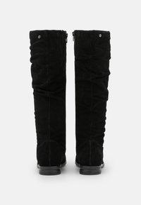 Czarne kozaki za kolano wykonane z miękkiego zamszu, z luźnym krojem, suwakiem z tyłu i płaską czarną podeszwą.