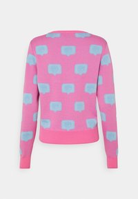 Pull en tricot rose avec des motifs de bulles de dialogue bleu clair. Encolure et poignets côtelés avec une coupe ajustée.