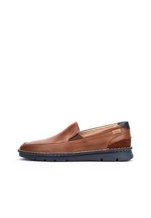 Zapato marrón de cuero tipo mocasín con punta redonda, paneles laterales elásticos y un talón de un azul oscuro contrastante, que presenta detalles de costura visibles.