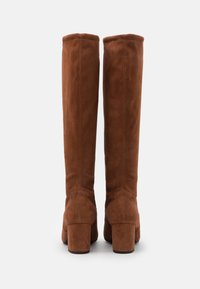 Bottes en daim marron hautes jusqu'au genou avec une texture lisse, des talons carrés et des coutures verticales au dos.