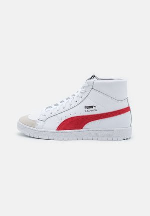 Hvid Puma høj-top-sneaker med rød sidestribe, grå tåbeskyttelse, hvide snørebånd og teksten "R. Sampson" på siden.