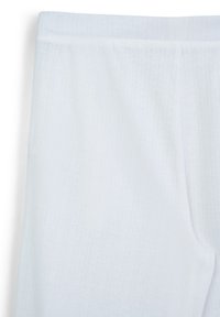 Pantalons en tissu texturé blanc avec une taille élastique et de subtiles lignes de couture verticales.