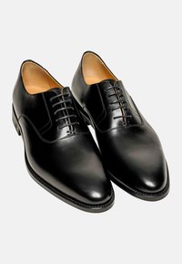 Schwarze Leder-Schuhe mit spitzem Zeh, Schnürdesign und glatter Textur. Besitzen ein dezentes Stichdetail entlang der Sohle.