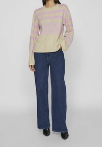 Randig stickad tröja i beige, rosa och lavendel; rund halsringning, ribbade ärmslut och nederkant. Kombinerad med vida mörkblå jeans.