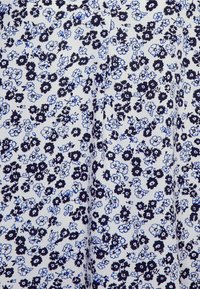 Tecido com padrão floral, com flores azul-marinho e azul claro sobre um fundo branco. O material parece macio e leve.