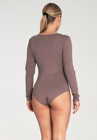 Body z długim rękawem w stonowanym brązowym kolorze, z okrągłym dekoltem i wysokimi wycięciami na nogawkach, gładka tekstura i dopasowany krój.