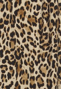 Tkanina s uzorkom leopard kože koja ima bež pozadinu s tamnosmešnim i crnim tačkama. Meko na dodir, s različitim veličinama i oblicima tačaka.